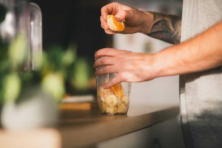 Preparing an orange beside a blender jug.