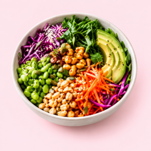 A Buddha bowl with avocado, grains, chickpeas and colourful vegetables on a soft pink background.