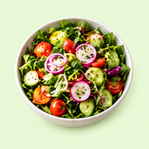 A bowl of fresh green salad with cucumber, tomatoes and radish on a pale green background.